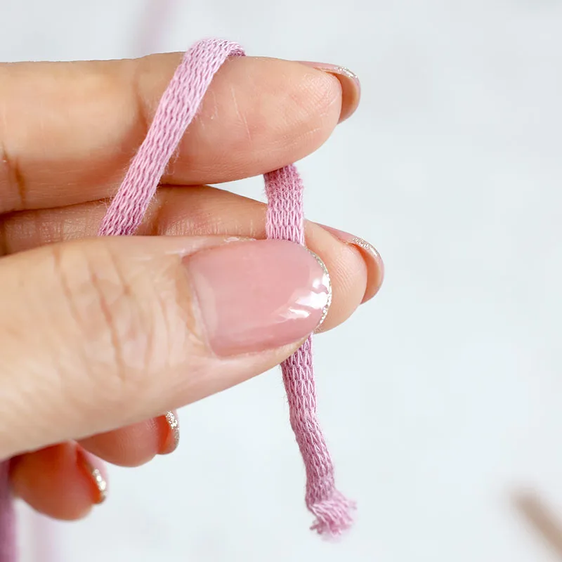 Place a piece of yarn on the palm of your left hand, leaving about 6 inches of yarn hanging off your index finger. Wrapping the yarn around the index finger. Use your thumb and middle finger to pinch the yarn's tail end.