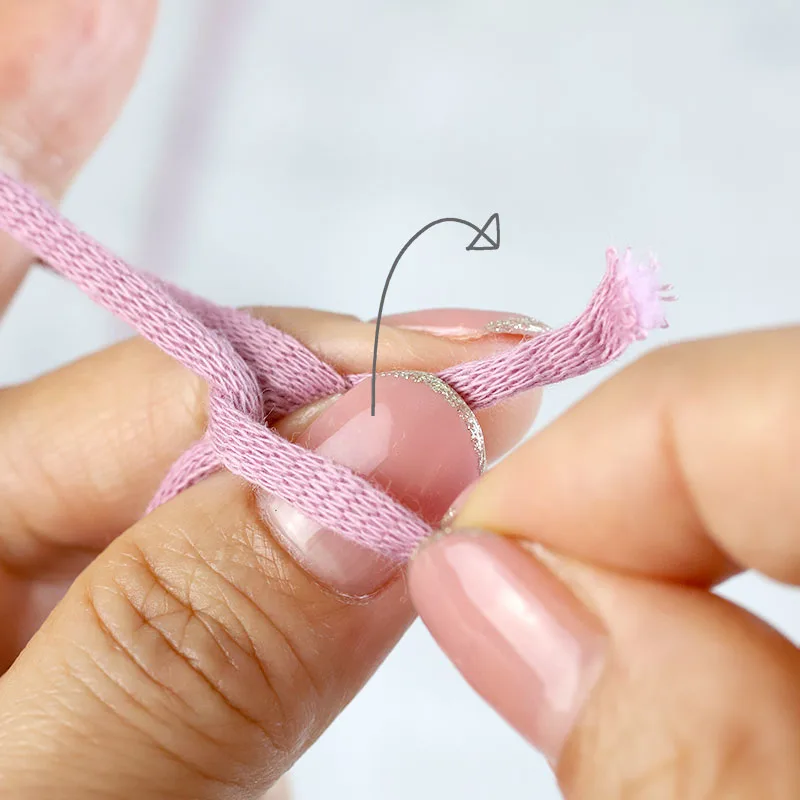 Pinch the yarn tail with your thumb and middle finger as well. Turn the loop on your left thumb over to the tail end of the yarn.