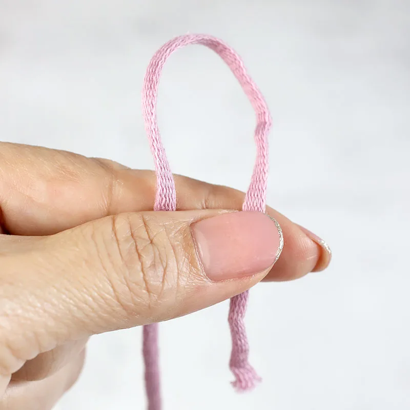 pinch to hang the yarn with the yarn tail end on the right of the yarn ball end, use your thumb and index finger of the left hand to pinch both strands to make loop above the fingers.
